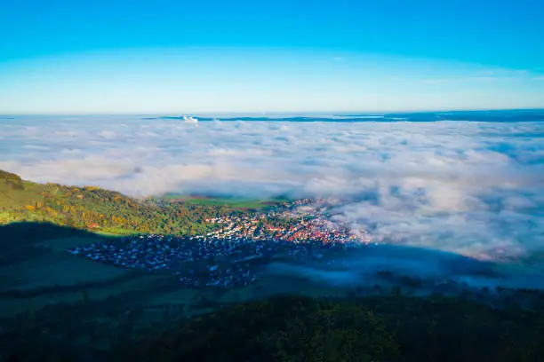 Germany, Bissingen an der teck city houses aerial panorama drone view above the buildings under foggy sea of clouds at sunrise