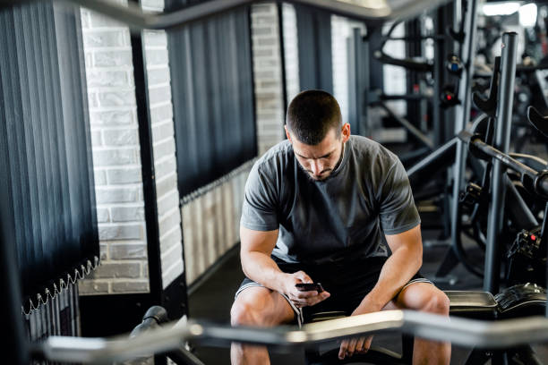 istock Male Bodybuilder Using His Smartphone In the Gym 1562297992