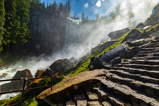 Staircase next to powerful flowing waterfall in nature. Vernal Falls trail, Yosemite Valley National Park during peak snowmelt 2023, California, USA.