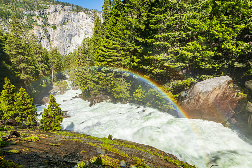 Nature spectacle of powerful flowing river into a valley with a rainbow. Vernal Falls trail, Yosemite Valley National Park during peak snowmelt 2023, California, USA.