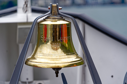 Close-up of golden bell with year 1928 engraved at paddle steamer passenger ship named City of Lucerne on a cloudy spring day. Photo taken May 18th, 2023, Brunnen, Switzerland.