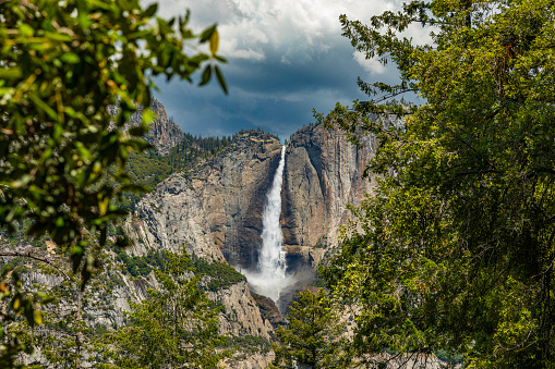 Yosemite Falls peak flow from snowmelt framed by nature on a sunny summer day in 2023, Yosemite Valley, National Park, California, USA.
