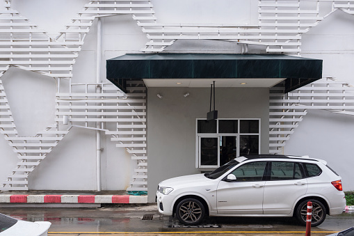 Samut Sakhon, Thailand - November 21/2020 : Customer in white car waiting for food in pickup area of Starbucks coffee Drive-thru restaurant in drizzling day