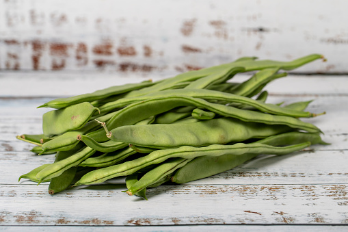 Green beans on a white wood background. Fresh raw string beans harvest season concept. Vegetables for a healthy diet