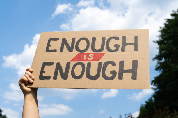 istock Hand holding placard sign with text Enough is enough at protest rally demonstration. 1562365625