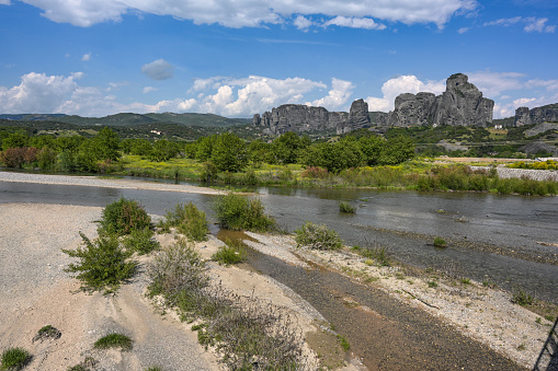 Low water in the riverbed of the Pinios near the mountains of Meteora, one of the longest rivers in Greece, dried after heat and drought, potential effect of climate warming, blue sky, copy space