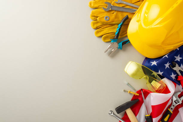 istock Patriotic Labor Day tribute. Top view image featuring the American flag, a construction helmet, work gloves, and building tools on light grey background. Perfect for ad honoring the American workforce 1562396617