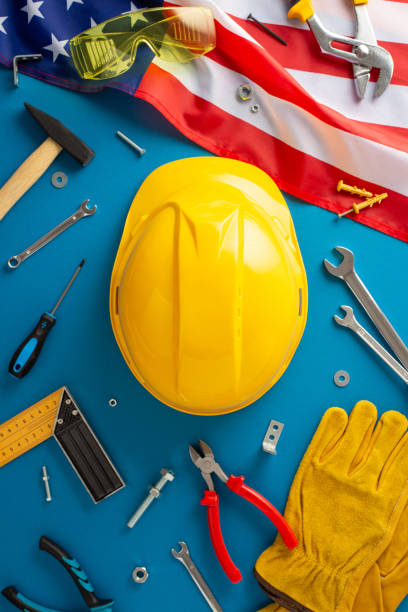 Labor Day automotive repair theme. Top view of USA flag, mechanic's tools, wrenches, socket set, screwdriver, spark plugs, gloves, safety glasses, helmet. Blue backdrop, space for auto repair services tema de reparación automotriz del día del trabajo. vista superior de la bandera de ee. uu., herramientas mecánicas, llaves, juego de enchufes, destornillador, bujías, guantes, gafas de seguridad, casco. fondo azul, espacio para servicios de reparación