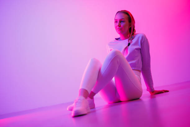 istock Thoughtful female sitting against neon pink background 1562424362