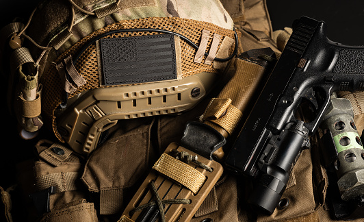 SpecOps tactical military gear with a plate carrier, combat knife, ballistic FAST helmet, flash-bang grenade, and Glock 17 handgun close up detail shots with US black flag