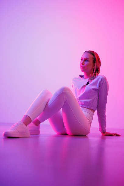 istock Thoughtful woman sitting against neon purple background 1562425448
