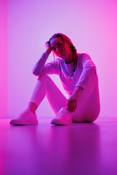 istock Contemplative woman sitting against purple background 1562425990