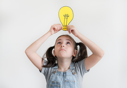 Girl Holding Light Bulb On Head on White Background