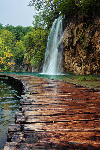 Wooden boardwalk through the waterfalls of Plitvice Lakes National Park in Croatia.