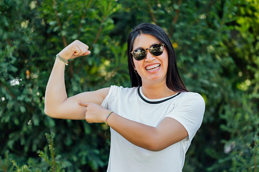 Young woman pointing to her arm .Power woman