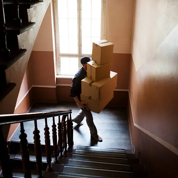 A courier carrying packages up stairway.