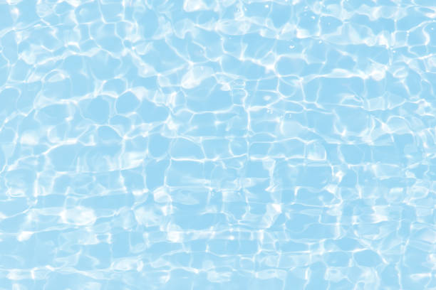 istock Blue water with ripples on the surface. Defocus blurred transparent blue colored clear calm water surface texture with splashes and bubbles. Water waves with shining pattern texture background. 1562490313