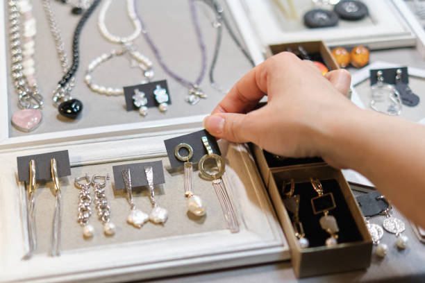 istock woman's hand delicately selects a handmade earring from a display, showcasing an array of artisanal jewelry in the background. supporting local artisans, and unique fashion accessories 1562507878