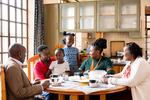 Nairobi family enjoying tea, chapatti, and conversation Waist-up view of 6 and 9 year old children, parents in 20s and 30s, and grandparents in early 60s sitting together in sunny dining room. kenyan culture stock pictures, royalty-free photos & images
