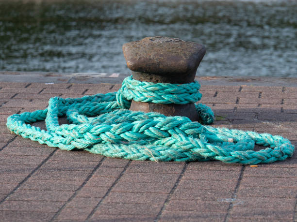 Close up rusty bollard with green ship rope