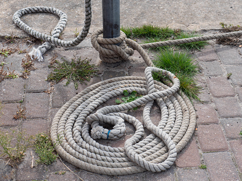 single loose knot of light coloured rope along bottom of frame on rustic wood background with copy space