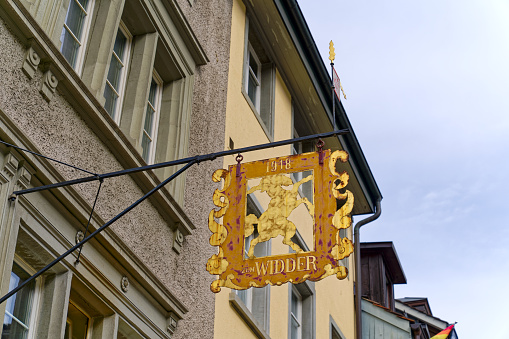 Facades of historic houses with golden sign with ram at the old town of Swiss City of Winterthur on a cloudy spring day. Photo taken May 17th, 2023, Winterthur, Switzerland.