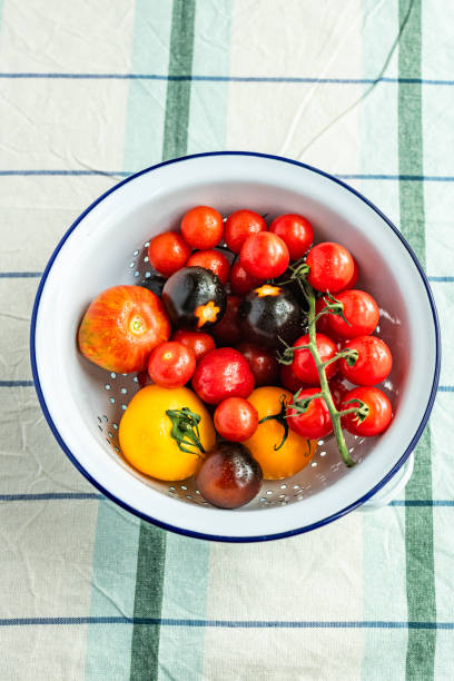 istock Various types of whole organic tomatoes in a white enamel colander 1562583836