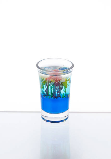 白い背景にミラーカウンターバーのショットグラスにクラゲカクテル。 - liqueur color image isolated nobody ストックフォトと画像