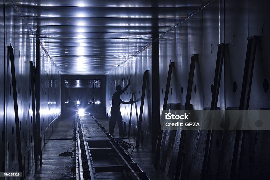 Operaio di fabbrica nella zona meno illuminata tunnel - Foto stock royalty-free di Spazio circoscritto