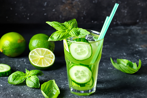 cold drink with basil, cucumber and lime. Mojito, lemonade with basil. Infused cucumber drink with mint. Detox water. Dark background.
