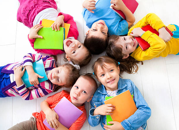 Kids in vibrant colored clothes laying with heads together stock photo