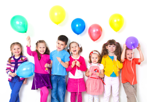Big group of happy children with balloons at white wall