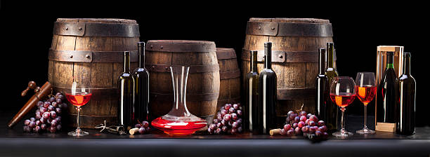 Still life of red grapes, wine bottles, casks and decanter stock photo