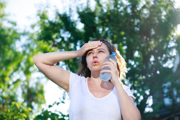 Young woman having hot flash and sweating in a warm summer day stock photo