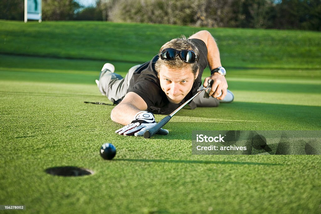 Giovane uomo utilizzando Golf Club in coda sul Verde biliardo - Foto stock royalty-free di Ambientazione esterna