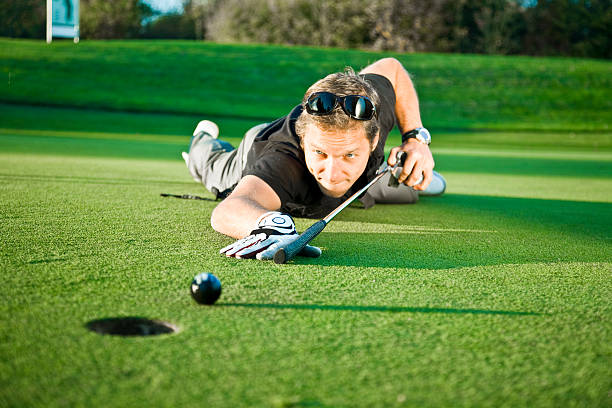 Young Man Using Golf Club as Billiard Queue on Green  billard queue stock pictures, royalty-free photos & images