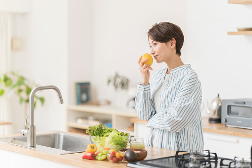An Asian woman is cooking in her home kitchen.
holding a lemon