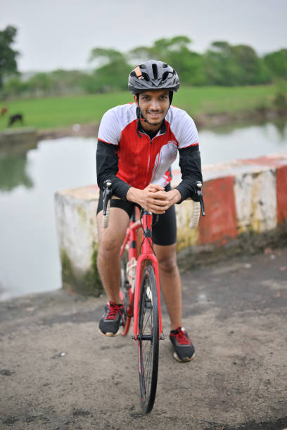 Active cyclist wearing protective gear, beaming with joy as he poses with his bicycle for the camera.