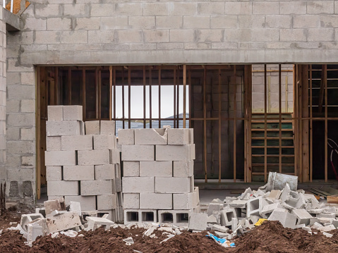 Concrete blocks in front of garage entrance to a single-family house under construction in a suburban development in southwest Florida. Light digital oil-painting effect.