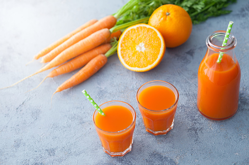 carrot and orange fresh juice on grey background - food and drink