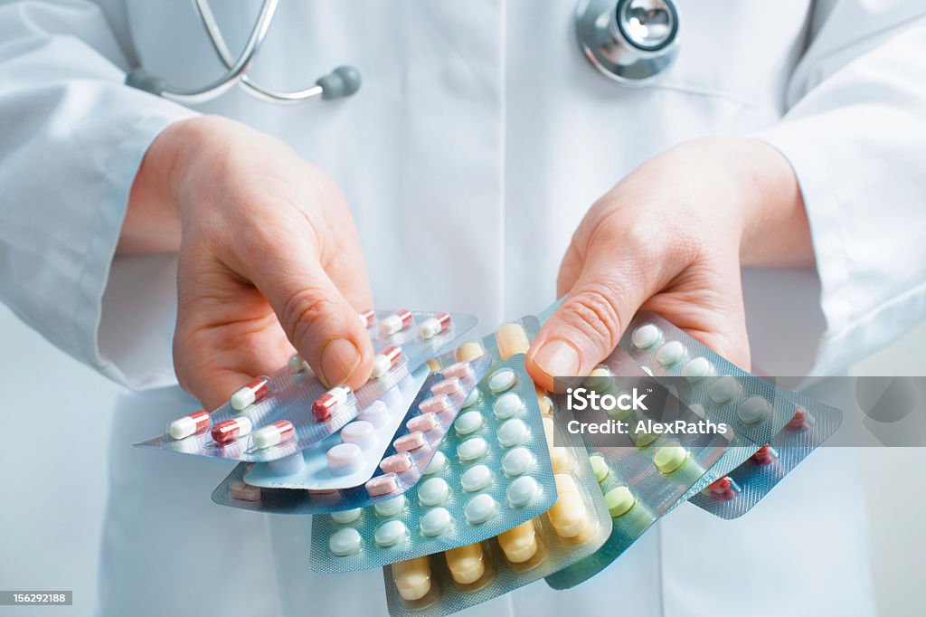 Doctor holding out several packs of a variety of pills Hand of doctors holding many different pills Medicine Stock Photo