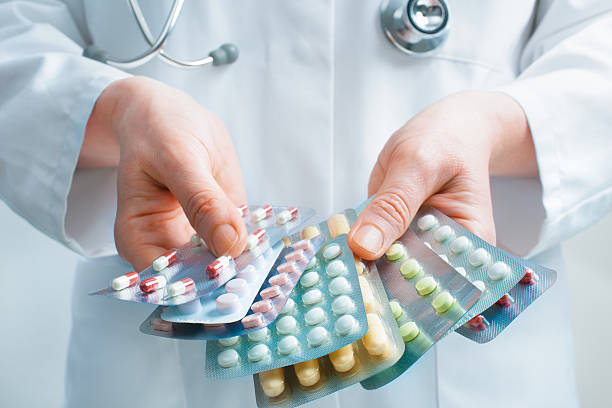 Doctor holding out several packs of a variety of pills stock photo