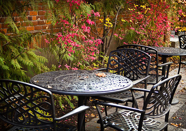 Fall Outdoor Patio Table and Chairs Black wrought iron tables outside with Colorful Fall Foliage against brick building peacful stock pictures, royalty-free photos & images