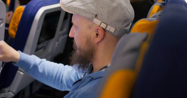 Concept digital technology on board the aircraft. Man uses digital technology to watch videos during flight. Airplane seat screen - digital technology that helps passengers not get bored during flight concepto de tecnología digital a bordo de la aeronave. el hombre utiliza la tecnología digital para ver videos durante el vuelo. pantalla del asiento del avión: tecnología digital que ayuda a los pasajeros a no aburrirse durante el vuelo