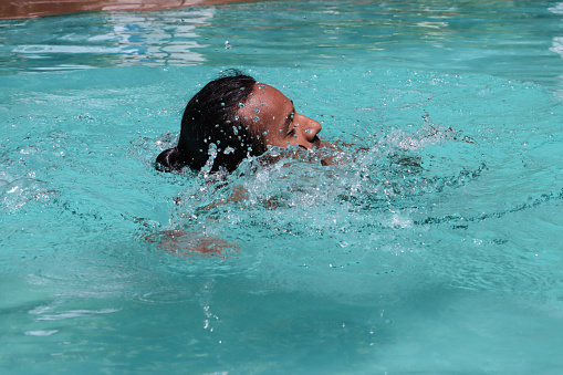 Young woman in water with hair splash. Blond woman in pool.