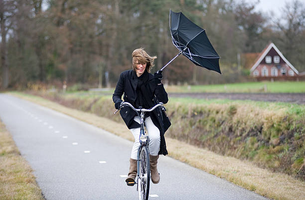 Fighting against the wind A young woman is fighting against the storm on her bicycle typhoon photos stock pictures, royalty-free photos & images