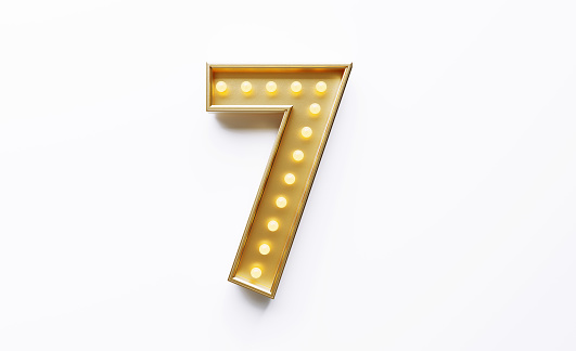 Gold colored number 7 illuminated by light bulbs on white background. Horizontal composition with copy space.