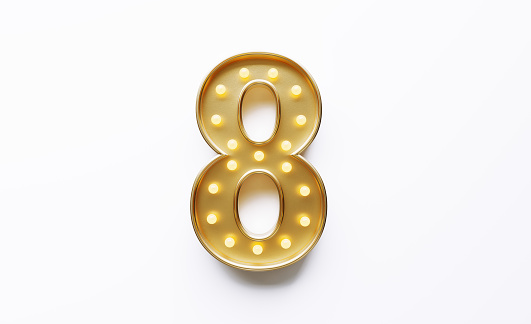Gold colored number 8 illuminated by light bulbs on white background. Horizontal composition with copy space.