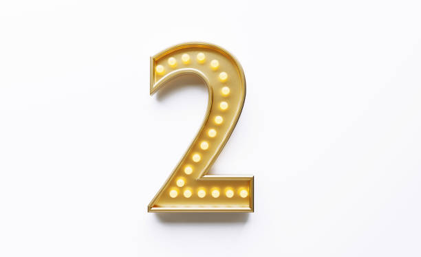 istock Gold Colored Number 2 Illuminated By Light Bulbs on White Background 1562968006