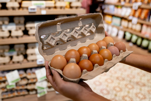 Close-up on woman holding a carton of eggs at the supermarket - grocery shopping concepts